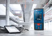 建設現場のコンクリート表面の測定値を表示するレーザー測定器とタブレット。