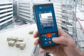 建設現場のバルコニーでレーザー測定器を使用している人。
