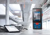 建設中の建物のコンクリートの表面にレーザー測定器とデジタルタブレットが置かれています。