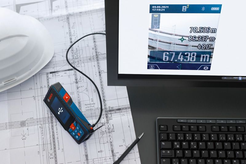 技術設計図の上にコンピューターに接続されたレーザー測定器。