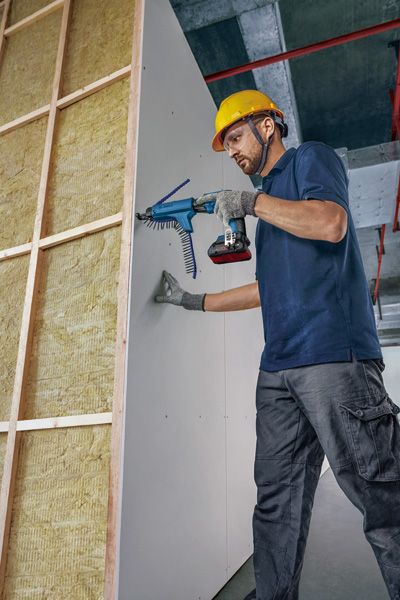 GTB 18V-45 安全装置を装着した人が自動スクリューガンを使用して乾式壁をフレームに固定します。.