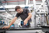 安全装置を装着した人が工業用組立ラインでコードレスドリルを使用しています。