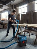 作業場で木材に電動工具を取り付けて真空抽出機を使用する人。