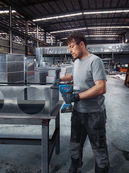 安全装置を装着した人が、コードレスリベットガンを使用して金属ダクトを固定します。.