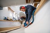 安全装備を身に着けた人が木製の船体の内部を研磨しています。