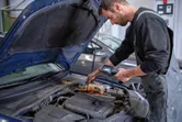 工場で検査カメラを使用して自動車のエンジンを検査している人。