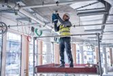 安全装備を身に着けた人が建設現場でコンクリートの天井に穴を開けています。.