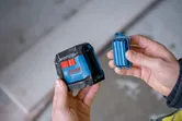レーザーレベルツールとバッテリーパックを持っている人。