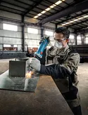 安全装備を身に着けた人が金属板にストレートグラインダーを使用しています。