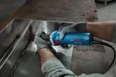 安全装備を身に着けた人がストレートグラインダーで溶接金属の継ぎ目を研磨します。
