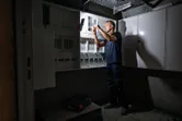 コードレス作業灯で照らされた電気パネルで作業する人。