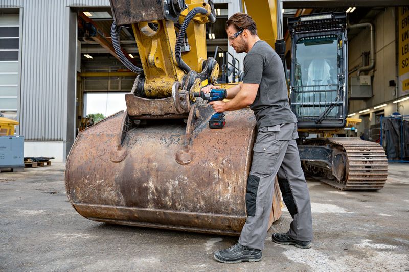 安全装備を装着した人が重機のインパクトレンチを使用しています。.