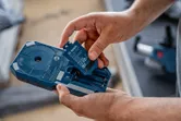 人が青い電動工具のハウジングにバッテリー パックを挿入します。