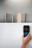 人は検出器を使用して壁をスキャンし、金属、木材、電気配線を探します。