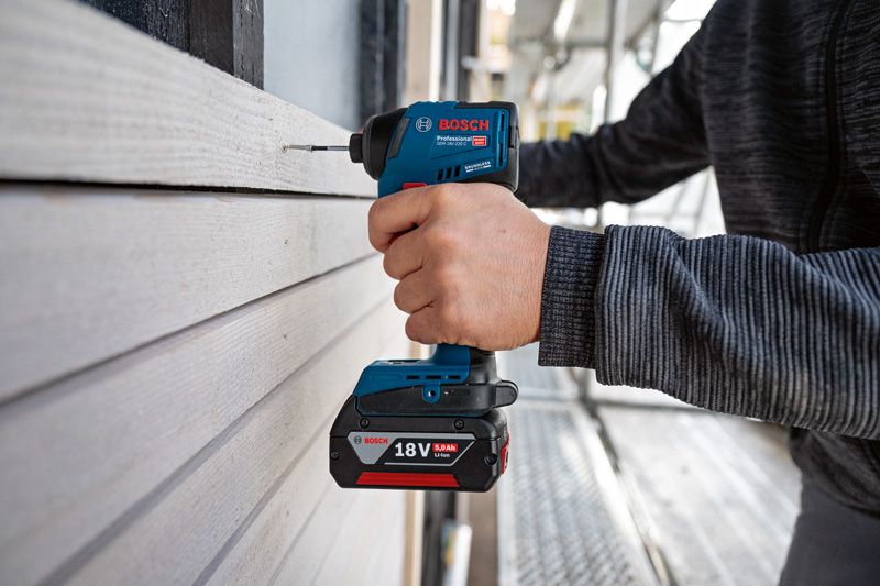 コードレス電動ドリルを使用して木製のサイディングに穴を開ける作業です。.