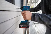 コードレス電動ドリルを使用して木製のサイディングに穴を開ける作業です。.