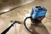 乾湿両用抽出機がタイル張りの床から水を吸い取ります。
