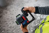 安全装備を身に着けた人が建設現場でレーザーレベルツールを調整しています。