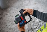 安全装置を装着し、バッテリーを取り付けたレーザーレベルツールを保持している人物。
