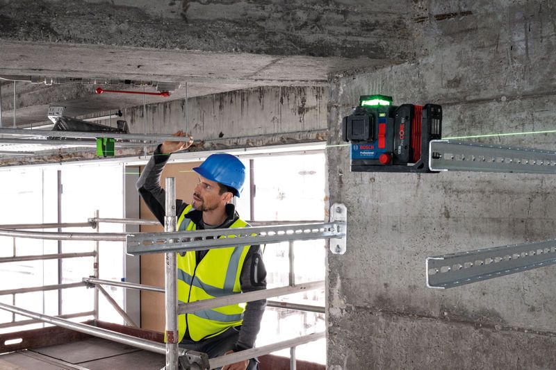 安全装置を装着した人がレーザーレベル測定ツールを使用して金属棒を位置合わせします。.