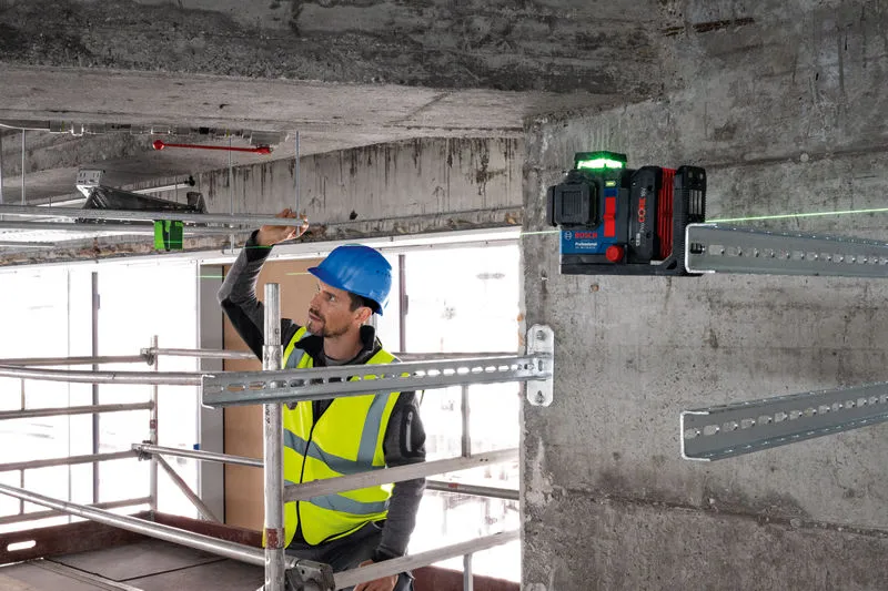 安全装置を装着した人がレーザーレベル測定ツールを使用して金属棒を位置合わせします。.