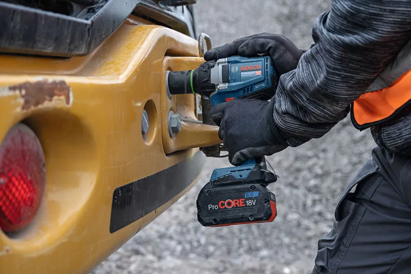 安全装置を装着した人が重機でコードレスインパクトレンチを使用しています。.