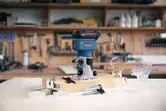 ワークショップの木製作業台に、コードレスパームルーターと付属品が展示されています。