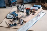 作業台にさまざまな木工アクセサリとアタッチメントを備えたコードレスパームルーター。