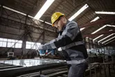 安全装置を装着した人が電動工具を使用して金属フレームにボルトを締めます。