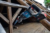 建設現場の木の梁の上に置かれたコードレスレシプロソー。.