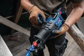 安全装置を装着した人が建設現場でレシプロソーを調整しています。