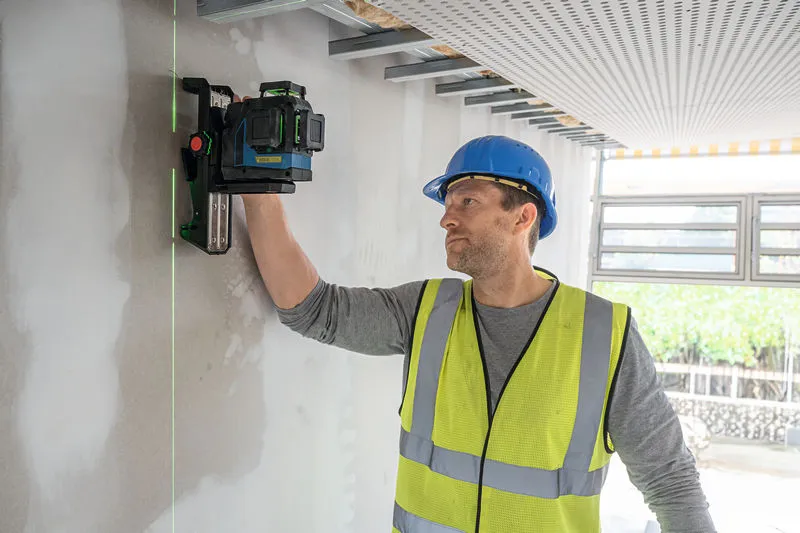 安全装置を装着した人がレーザーレベルツールを壁に合わせます。.