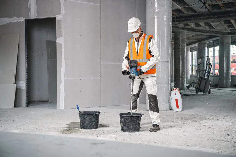 安全装置を装着した人が攪拌機構を使用してバケツ内の材料を混ぜます。.