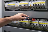 非接触型電圧テスターを使用して電気パネルをテストしている人。