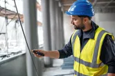 安全装置を装着した人が非接触型電圧テスターを使用してケーブルをテストします。