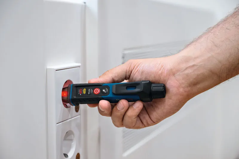 人が電気コンセントの近くで非接触型電圧テスターを使用しています。.