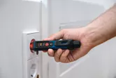 人が電気コンセントの近くで非接触型電圧テスターを使用しています。