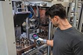安全装備を身に着けた人がサーマルカメラで産業機械を検査しています。.