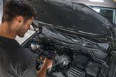 手持ち式サーモカメラを使用して自動車のエンジンを検査する人。.