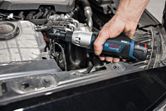 コードレスラチェットレンチを使用して、自動車エンジン内のボルトを締めます。