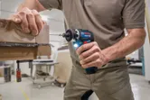 コードレスドライバーを使用して、積み重ねられた木材にネジを締める人。.