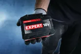 手袋をはめた手にBosch Expert 18V 15Ahバッテリーパック。.