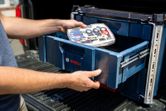 作業員が工具箱を収納するために、工具収納用の引き出し式ケースシステムをスライドさせて開ける。