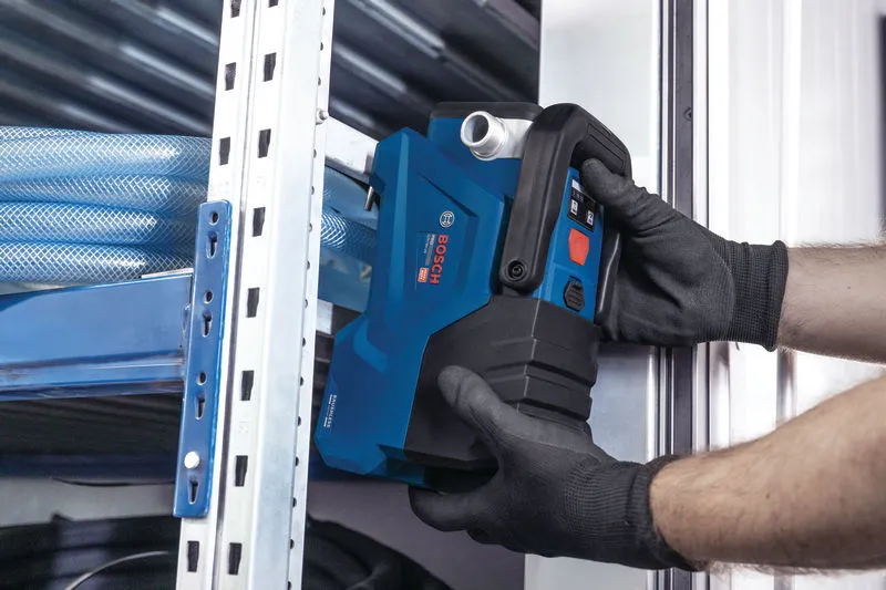 安全装置を装着した人が金属製の棚の近くに青い電動工具を設置しています。