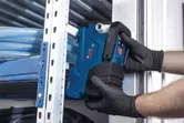 安全装置を装着した人が金属製の棚の近くに青い電動工具を設置しています。