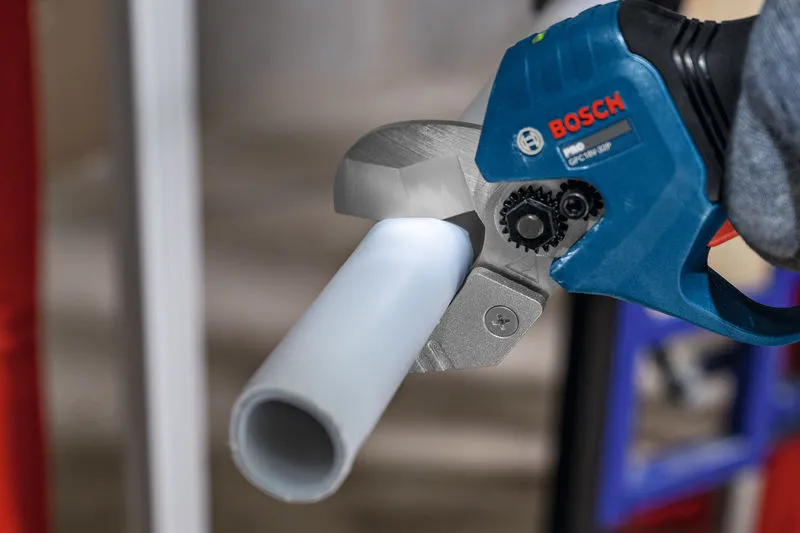 コードレスパイプ剪断機を使用してプラスチックパイプを切断する人。