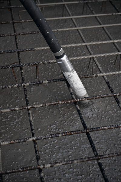 コンクリートバイブレーターが、鉄筋グリッド上に注入したばかりのコンクリートを固めます。