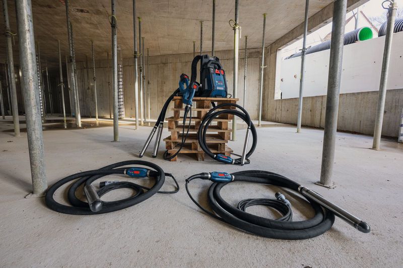 パレット上に 2 つのコンクリート バイブレーターとバックパック電源を備えた建設現場。