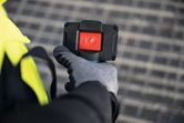 安全装置を装着した人が、大きな赤い電源ボタンの付いたデバイスを持っています。