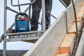 安全装備を身に着けた人が、携帯型電源装置の横にある足場の上に立っている。